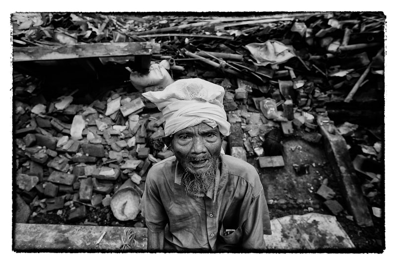 Indonesian man outside his earthquake damaged home