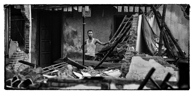 Indonesia man looks at earthquake damaged home